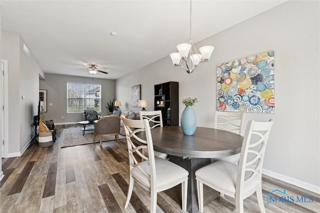 dining space with wood finished floors, visible vents, baseboards, and ceiling fan with notable chandelier