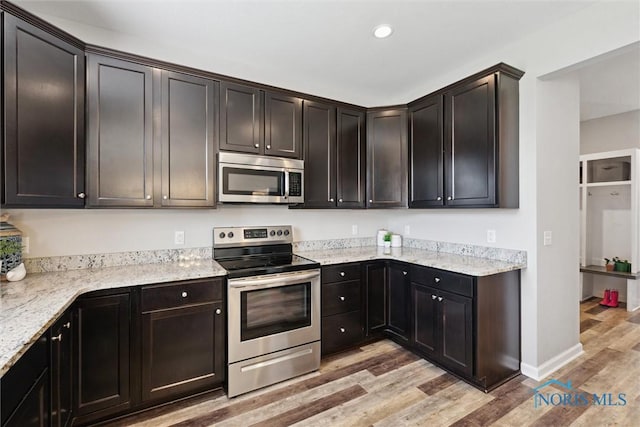kitchen with recessed lighting, light stone countertops, stainless steel appliances, and light wood-type flooring