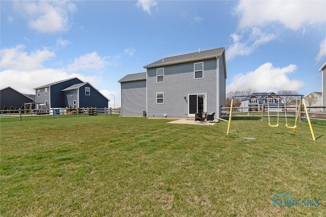 rear view of property featuring a patio area, a lawn, a playground, and fence
