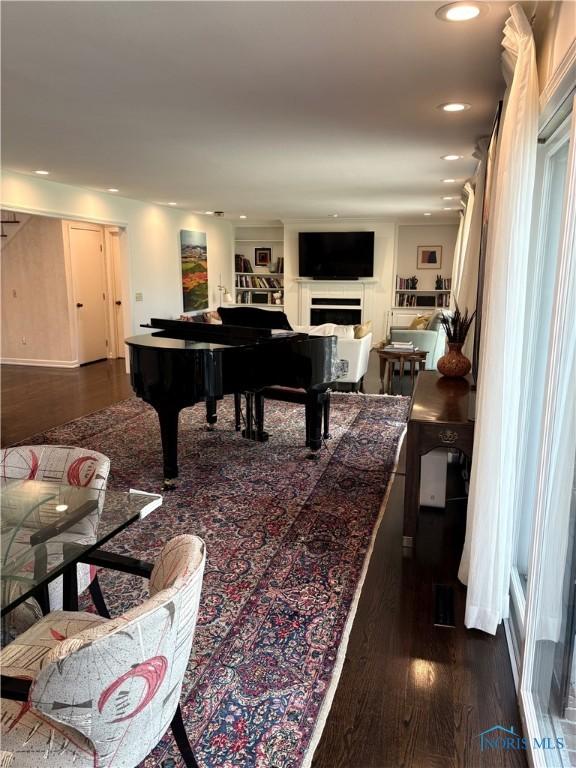 interior space with a fireplace, recessed lighting, and dark wood-type flooring