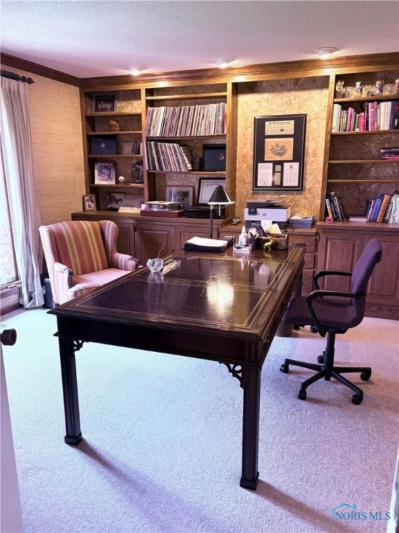 carpeted office space featuring ornamental molding, built in shelves, and a textured ceiling
