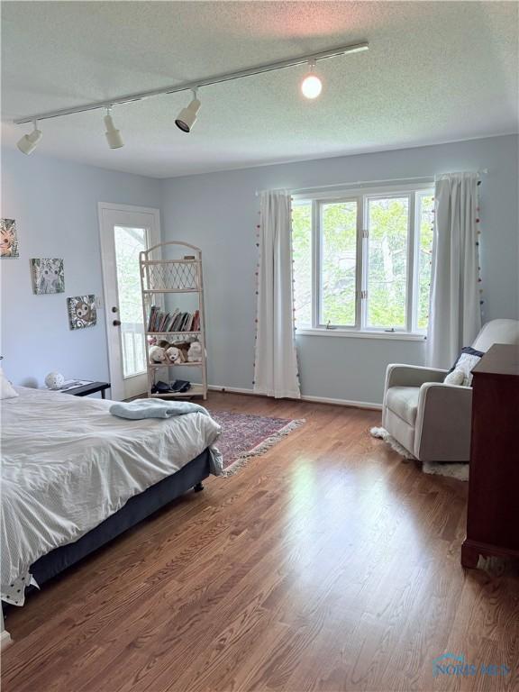 bedroom featuring a textured ceiling, track lighting, and wood finished floors