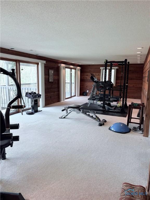 exercise area with wood walls, carpet, and a textured ceiling