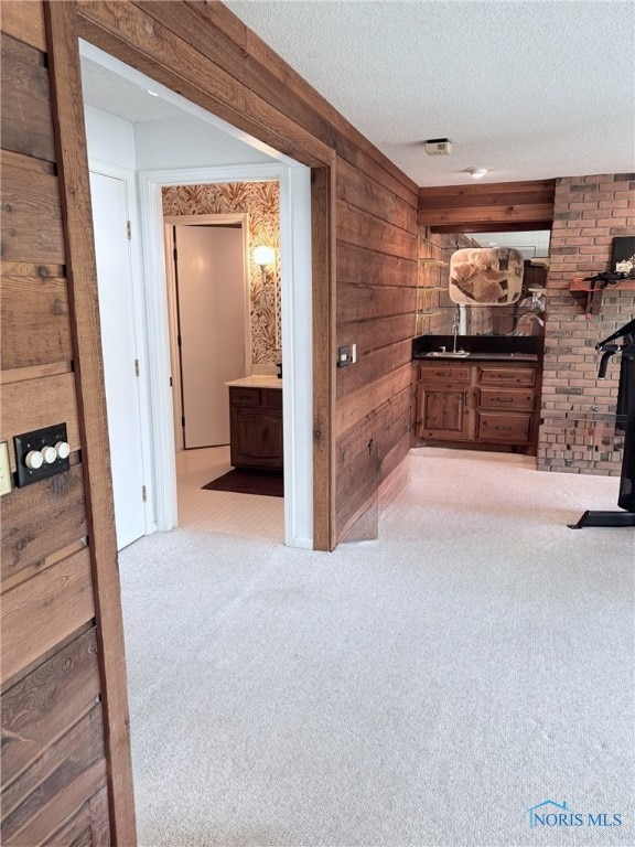 corridor with wooden walls, a textured ceiling, and carpet flooring