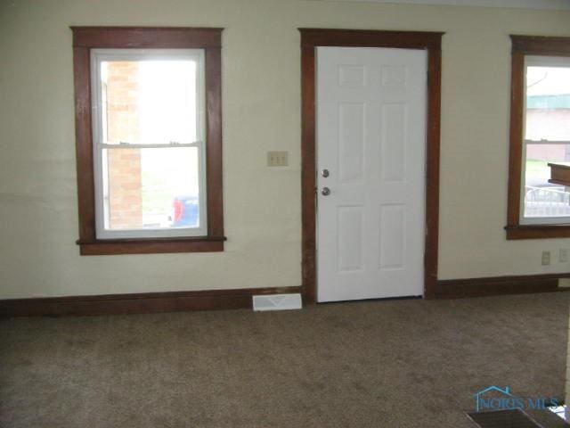 carpeted entryway with a healthy amount of sunlight, baseboards, and visible vents