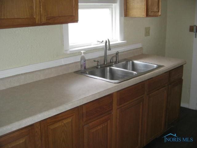 kitchen featuring light countertops, a sink, and brown cabinets