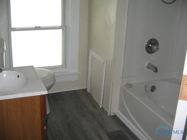 full bathroom featuring wood finished floors, tub / shower combination, vanity, and toilet