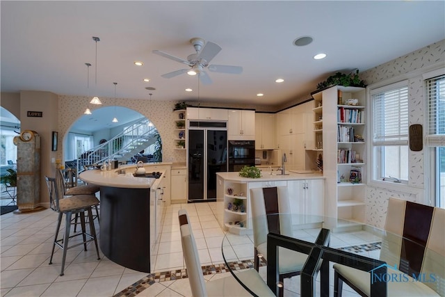 kitchen with open shelves, a peninsula, high end black fridge, and wallpapered walls