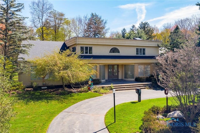 view of front of house with stucco siding, a front lawn, and french doors