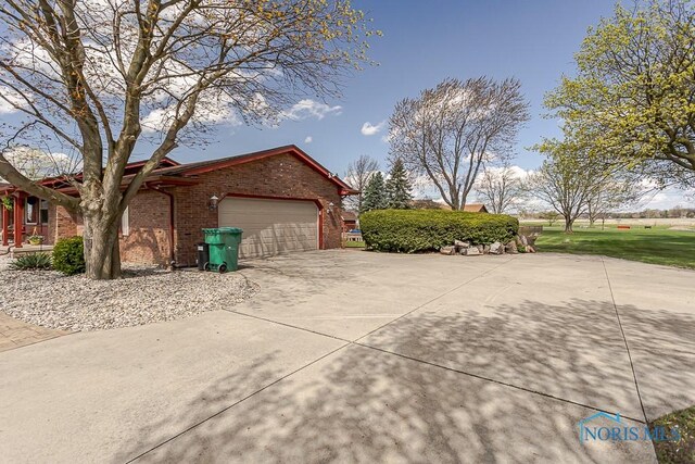 view of property exterior with brick siding, driveway, and a garage