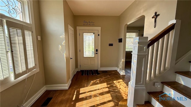 foyer featuring arched walkways, wood finished floors, visible vents, and baseboards