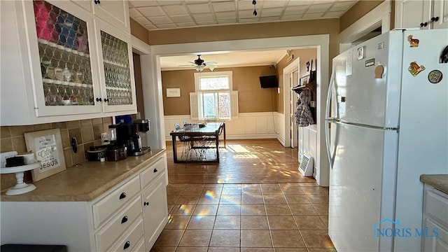 kitchen with glass insert cabinets, white cabinetry, a wainscoted wall, and freestanding refrigerator