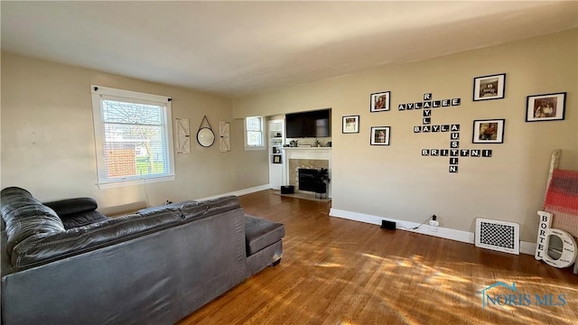 living room with baseboards, dark wood-style flooring, visible vents, and a fireplace