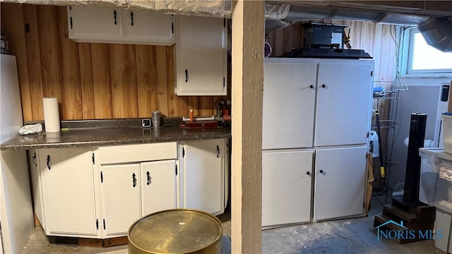 kitchen featuring white cabinets, dark countertops, and wooden walls