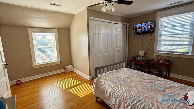 bedroom with baseboards, wood finished floors, visible vents, and multiple windows