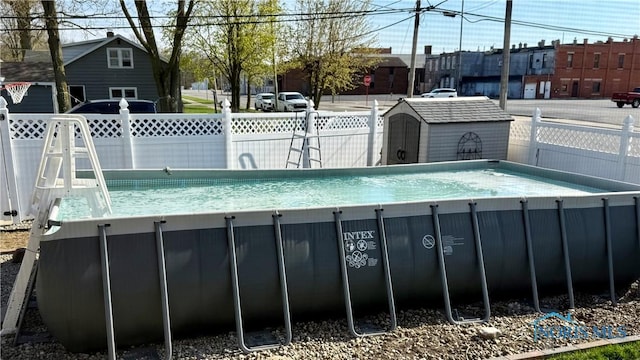 view of swimming pool with a fenced in pool, a fenced backyard, a storage unit, and an outbuilding