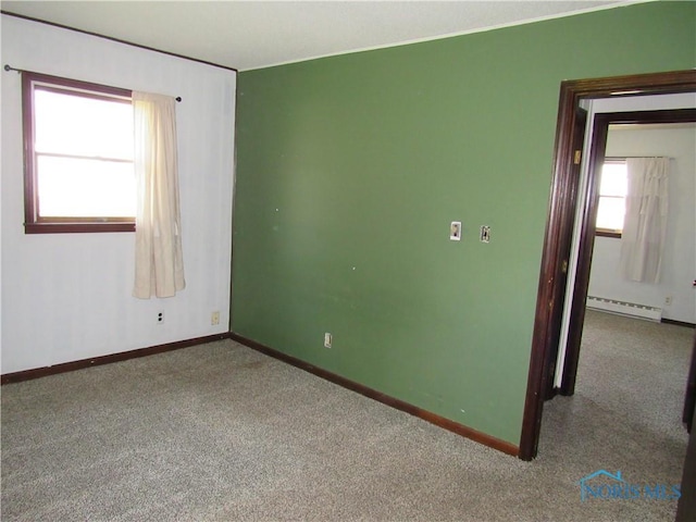 carpeted empty room with baseboard heating and baseboards