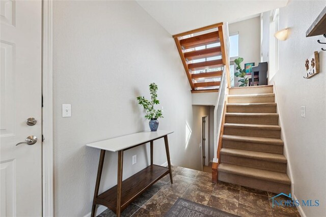 staircase featuring baseboards and stone finish flooring