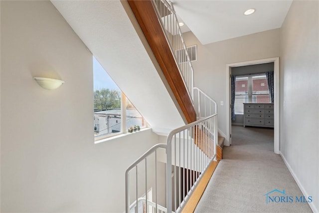 hall featuring visible vents, carpet flooring, baseboards, and an upstairs landing