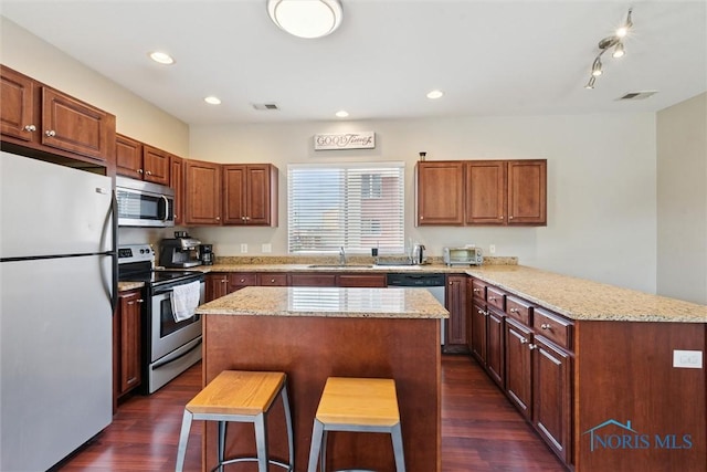 kitchen with dark wood-style flooring, a sink, stainless steel appliances, a peninsula, and visible vents
