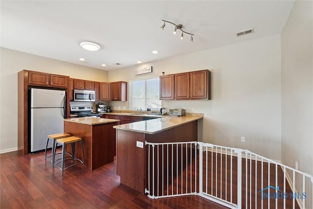 kitchen featuring a kitchen breakfast bar, stainless steel appliances, dark wood-type flooring, and visible vents