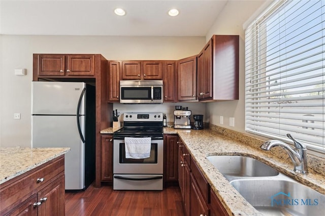 kitchen featuring light stone countertops, dark wood-type flooring, recessed lighting, a sink, and stainless steel appliances