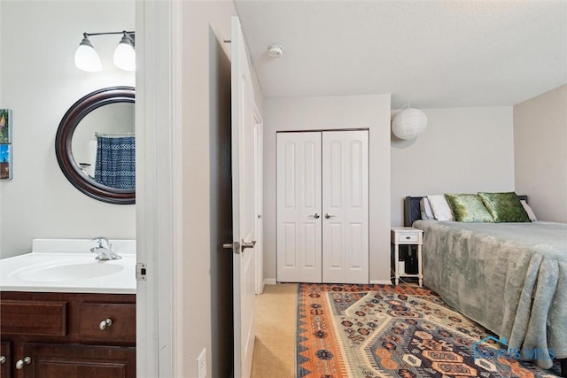 bedroom with a closet, a sink, and light carpet