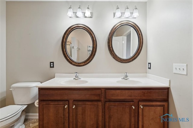 bathroom featuring double vanity, a sink, and toilet