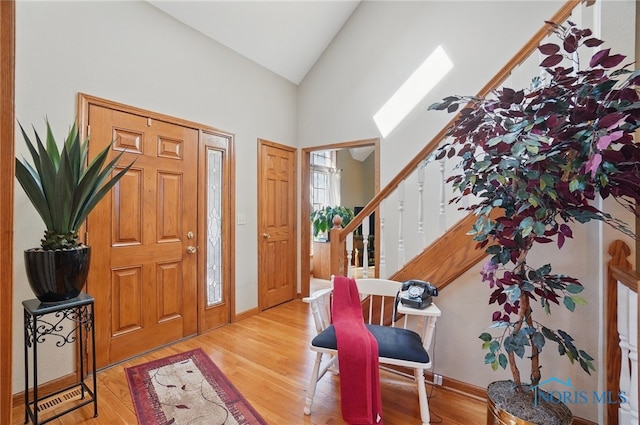 entryway with high vaulted ceiling, stairs, wood finished floors, and baseboards