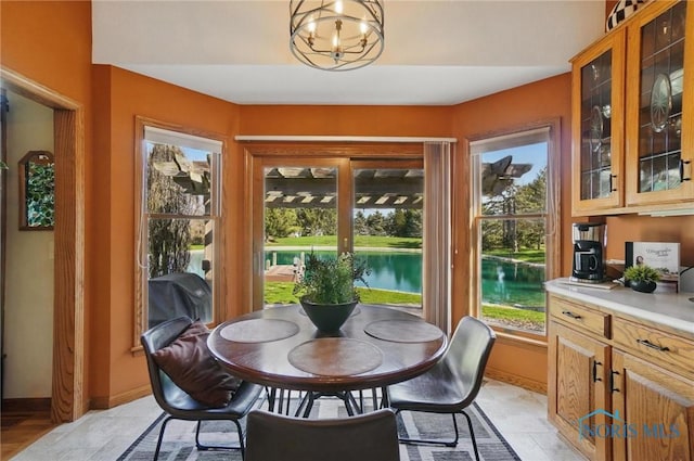 dining room featuring a chandelier, a water view, and baseboards
