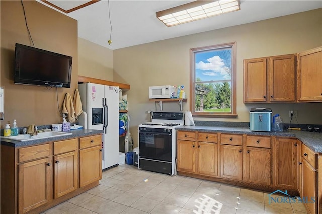 kitchen with brown cabinets, dark countertops, a sink, and white appliances