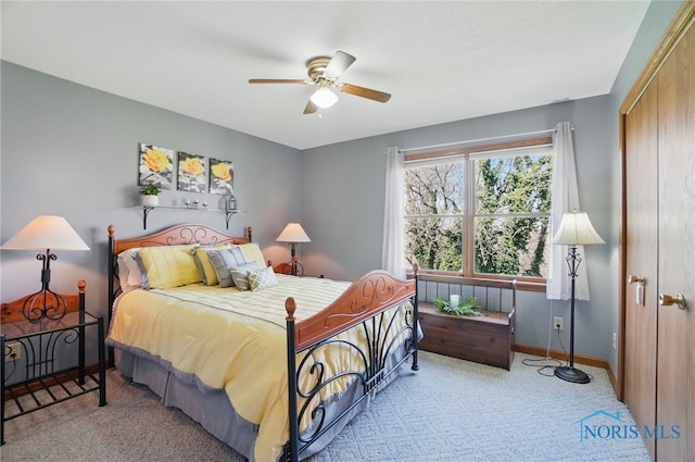 carpeted bedroom with a closet, baseboards, and ceiling fan