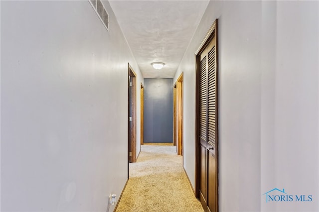 hall featuring carpet floors, visible vents, and baseboards