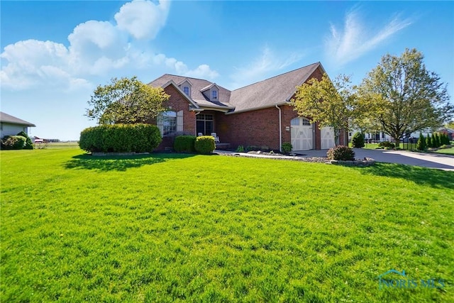 view of front facade with brick siding, a front lawn, an attached garage, and concrete driveway