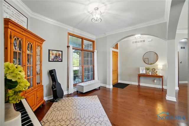 foyer with visible vents, arched walkways, crown molding, and dark wood-type flooring