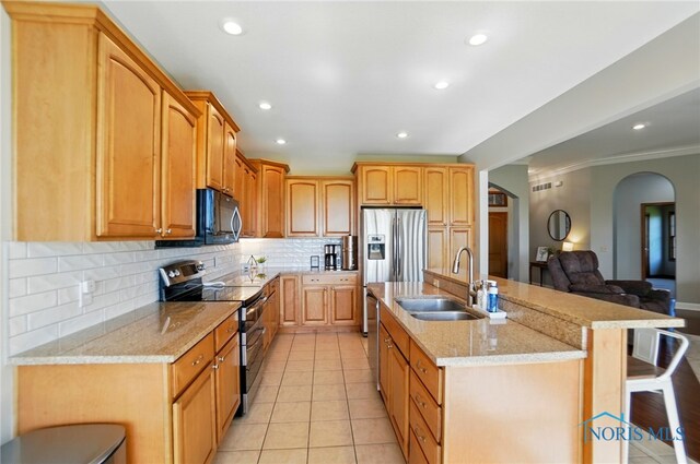 kitchen with open floor plan, a kitchen breakfast bar, tasteful backsplash, a sink, and appliances with stainless steel finishes