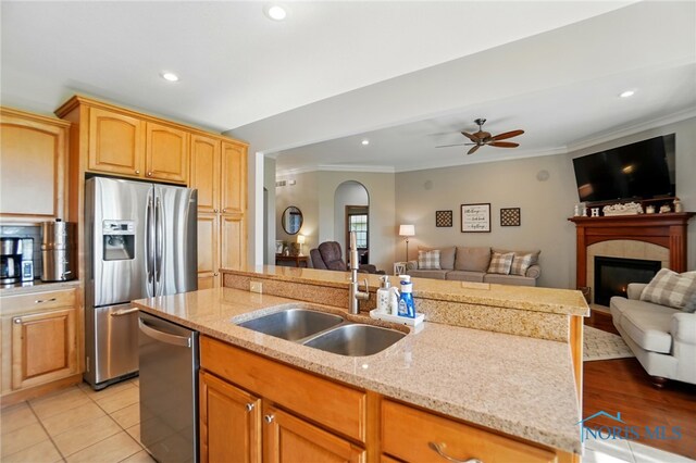 kitchen with open floor plan, appliances with stainless steel finishes, ornamental molding, and a sink