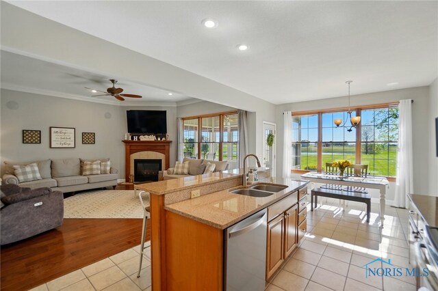 kitchen with a glass covered fireplace, dishwasher, a breakfast bar area, a sink, and light tile patterned floors