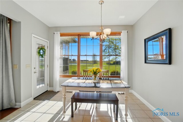 dining space featuring an inviting chandelier, baseboards, and light tile patterned flooring