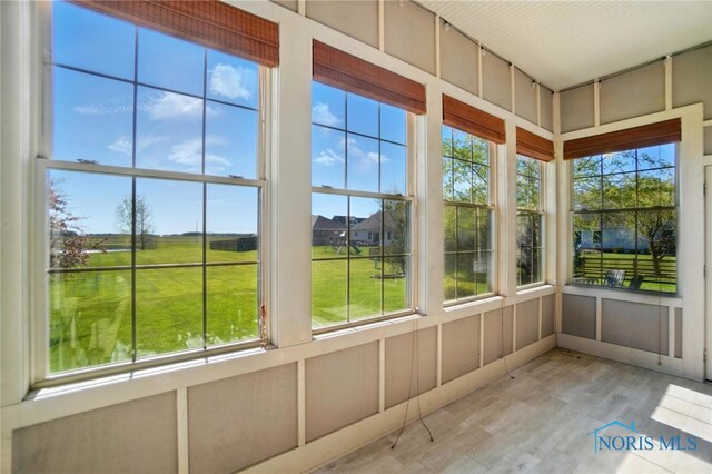 unfurnished sunroom featuring wood finished floors and a healthy amount of sunlight