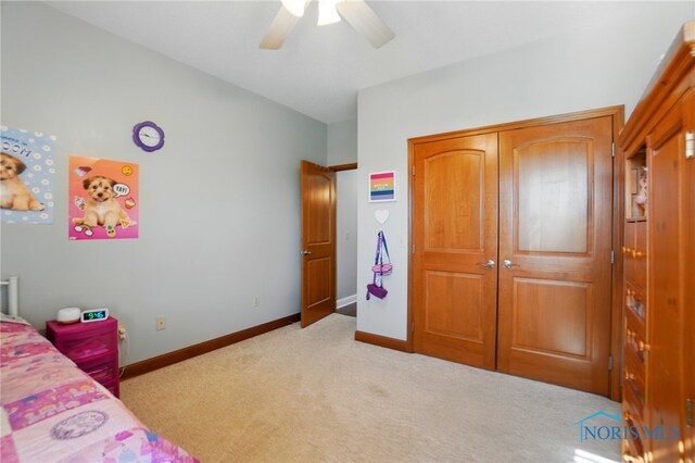 bedroom featuring light colored carpet, a ceiling fan, baseboards, and a closet