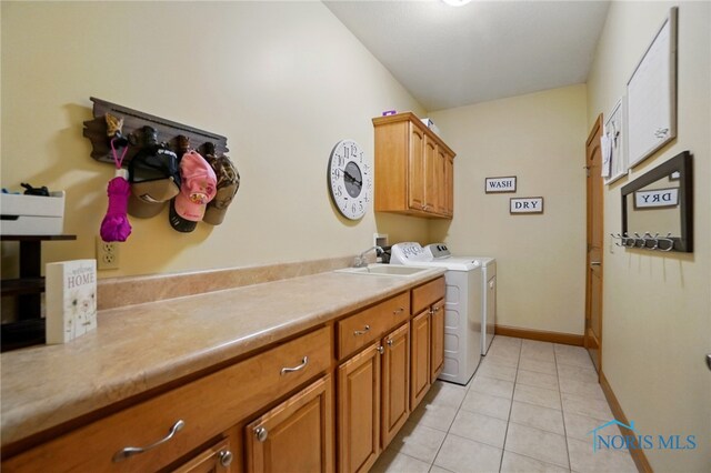 washroom with baseboards, a sink, cabinet space, independent washer and dryer, and light tile patterned floors