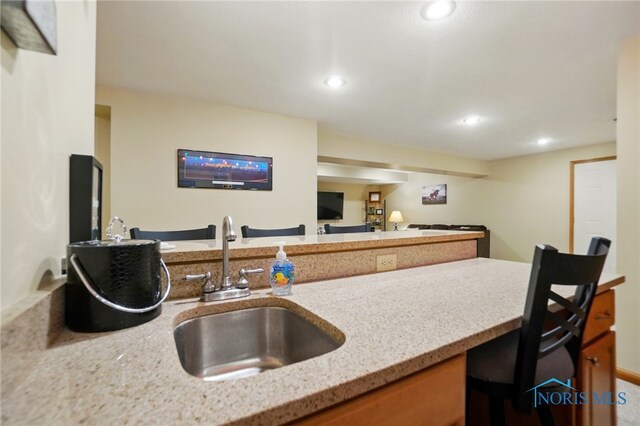 kitchen with recessed lighting, a sink, a peninsula, and light stone countertops