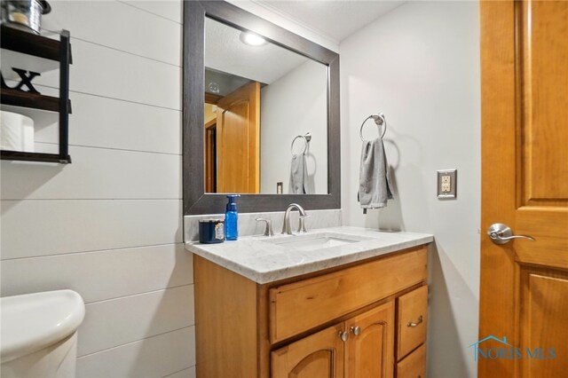 half bathroom featuring vanity and toilet