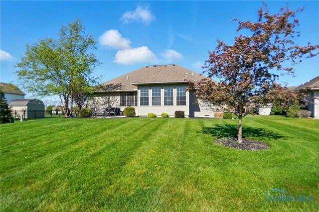 back of house featuring a lawn, fence, and a shingled roof