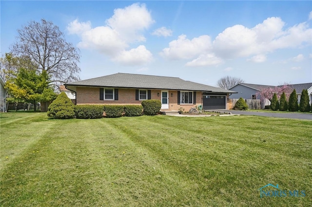 ranch-style house featuring an attached garage, a front lawn, brick siding, and aphalt driveway