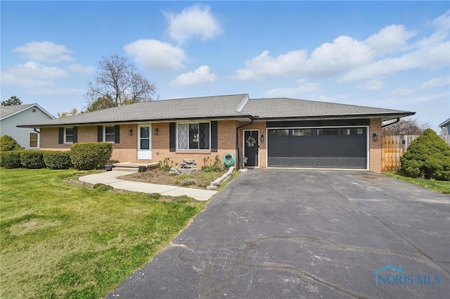 view of front of house featuring brick siding, an attached garage, driveway, and a front yard