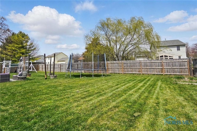 view of yard featuring a playground, a fenced backyard, and a trampoline