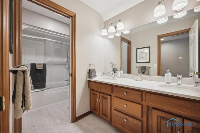 full bath featuring a sink, bath / shower combo with glass door, double vanity, and toilet