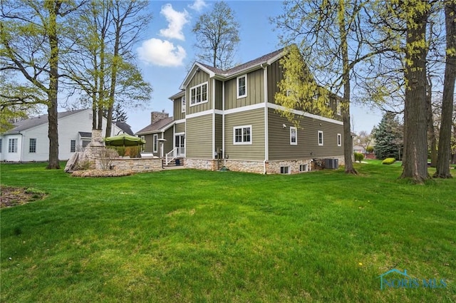 back of property featuring a lawn, cooling unit, and board and batten siding